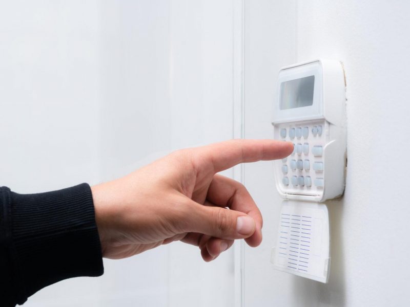 Hand entering alarm system password of an apartment, home or business office. Surveillance and protection console against rubbery and thief